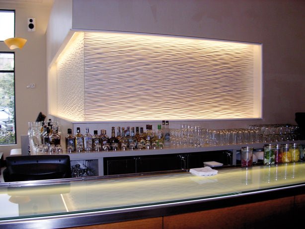 Modern bar area accented with an ocean wave 3D MDF wall panel and overhead lighting