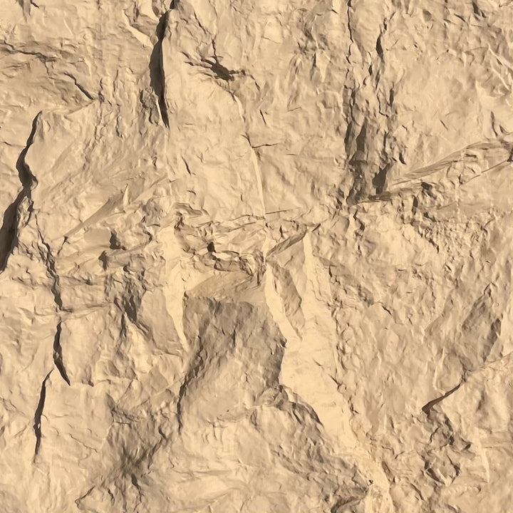 A close-up of the rock texture with deep shadows and creases filling the frame.